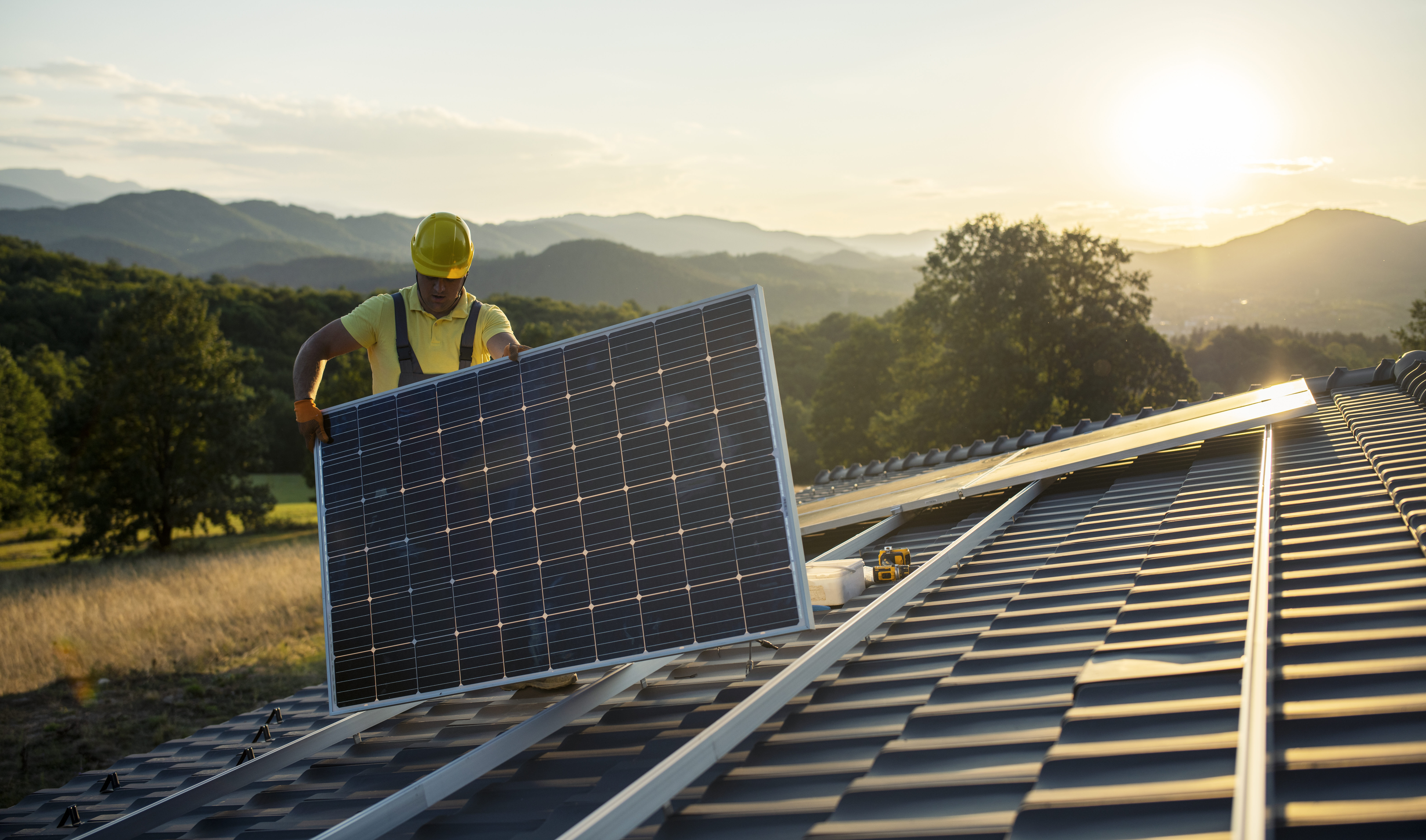 Technician fitting solar panels to a house roof.