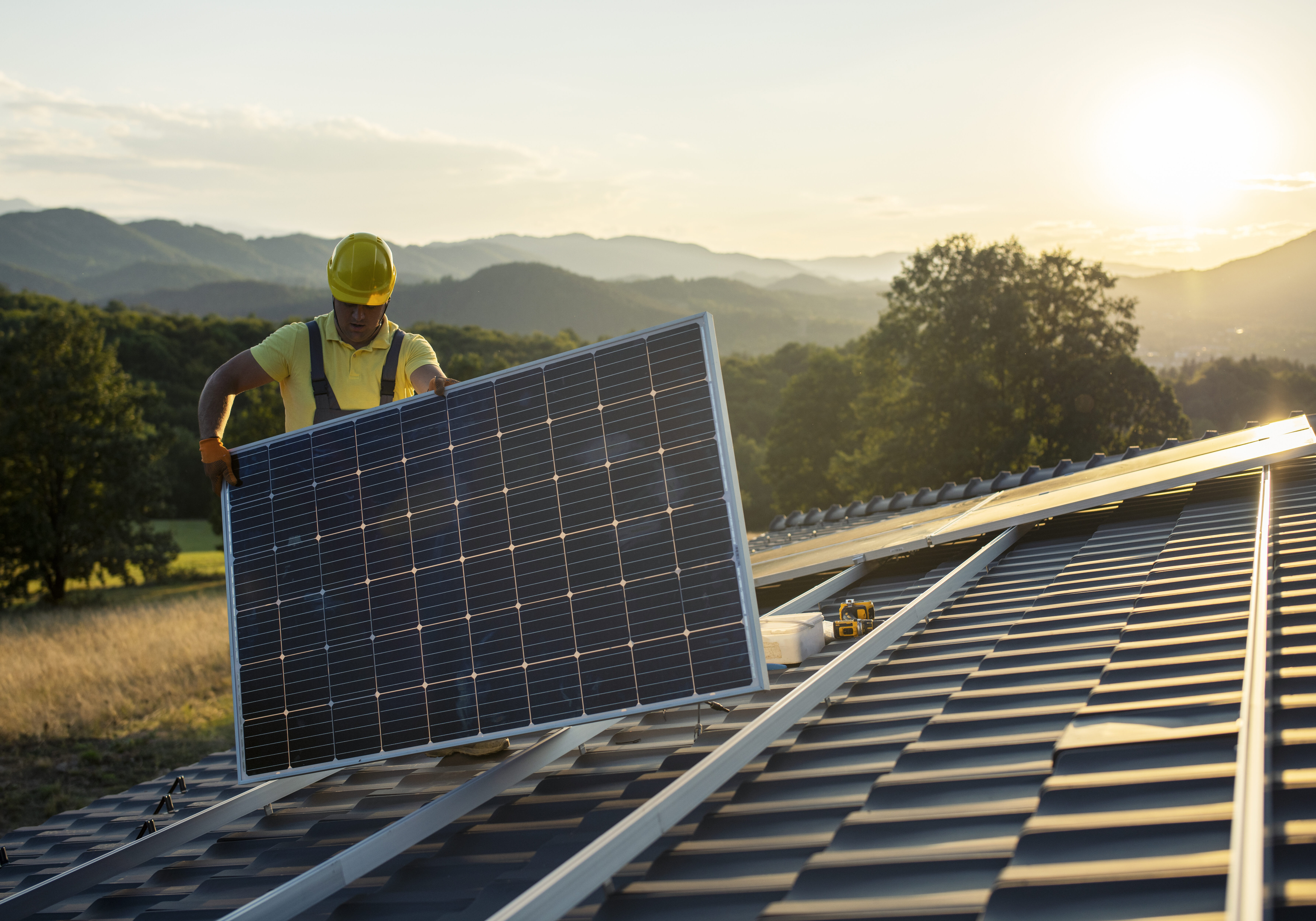 Technician fitting solar panels to a house roof. Technician fitting solar panels to a house roof.