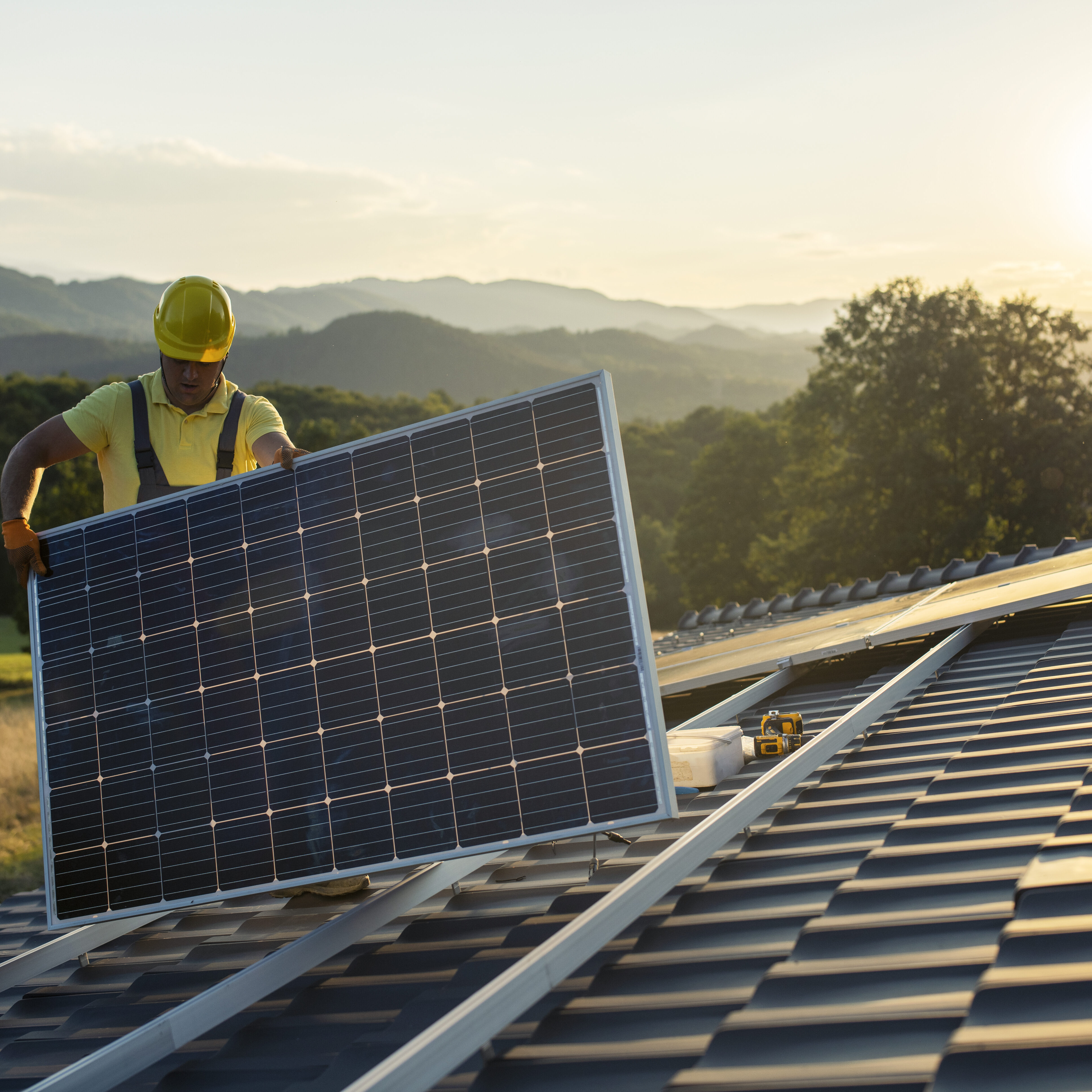 Technician fitting solar panels to a house roof. Technician fitting solar panels to a house roof.